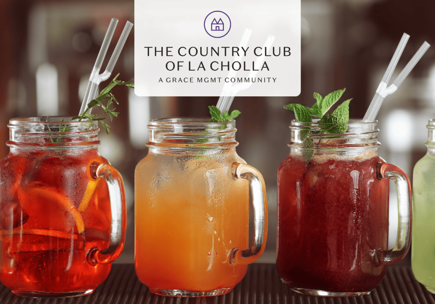 Three colorful iced drinks in mason jars with mint garnish on a bar, with a white logo card overhead reading The Country Club of La Cholla (branding image).