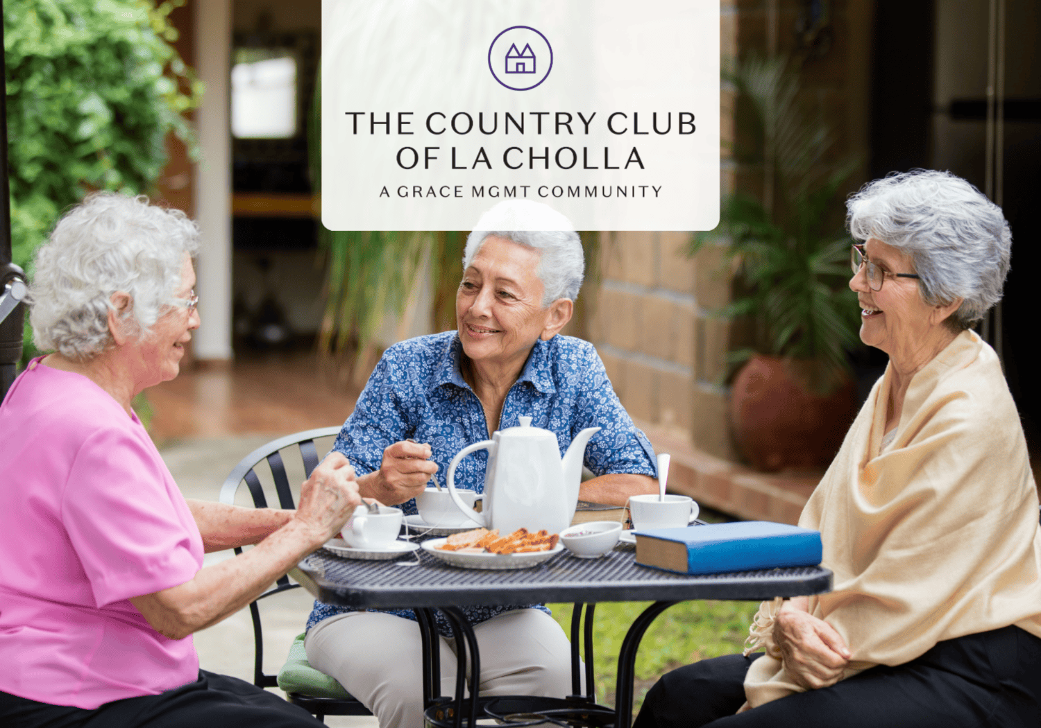 Three smiling senior women share tea at an outdoor patio table at The Country Club of La Cholla.