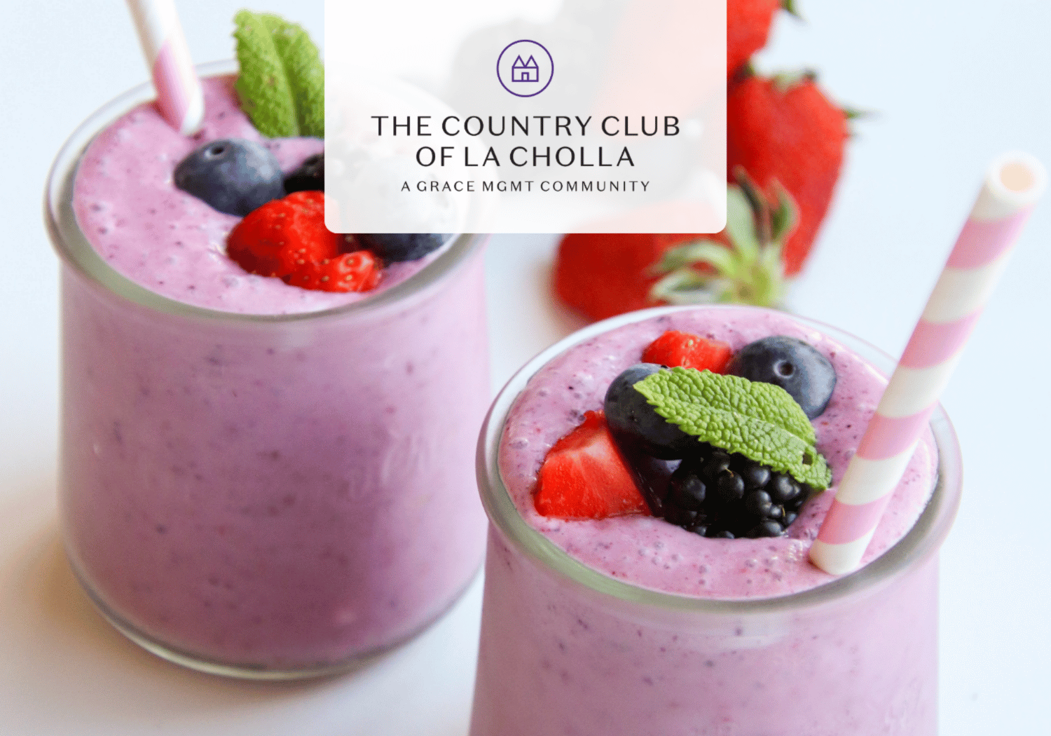 Two pink berry smoothies topped with strawberries, blueberries, and mint, with The Country Club of La Cholla logo centered over the image.