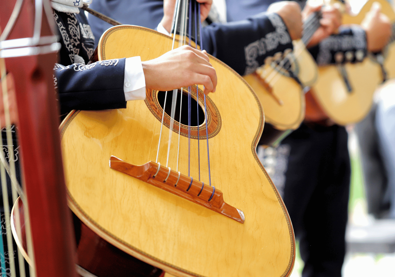 Close-up of a guitarist's hand plucking the strings of a wooden classical guitar.