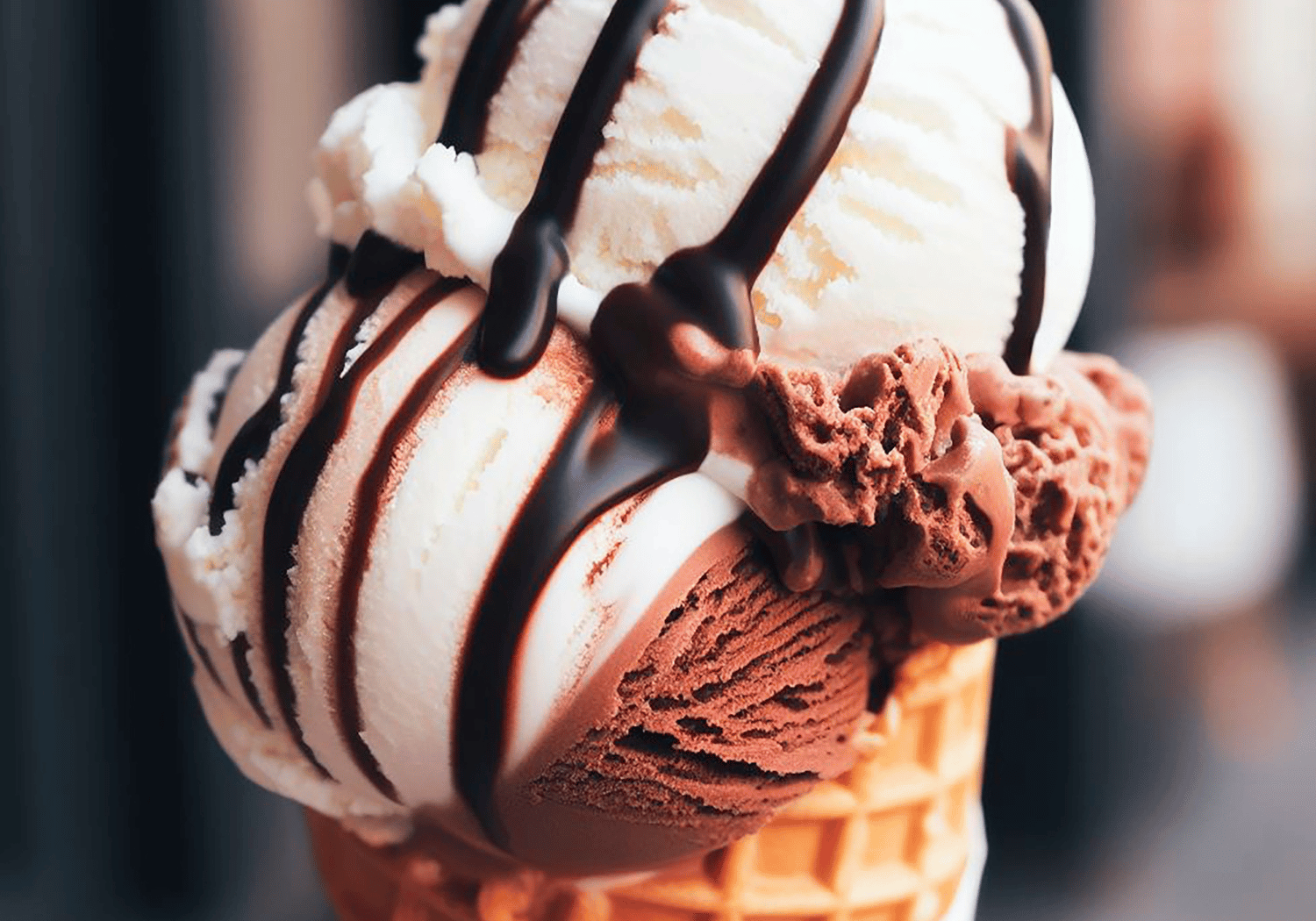 Ice cream cone with vanilla and chocolate scoops drizzled in chocolate sauce